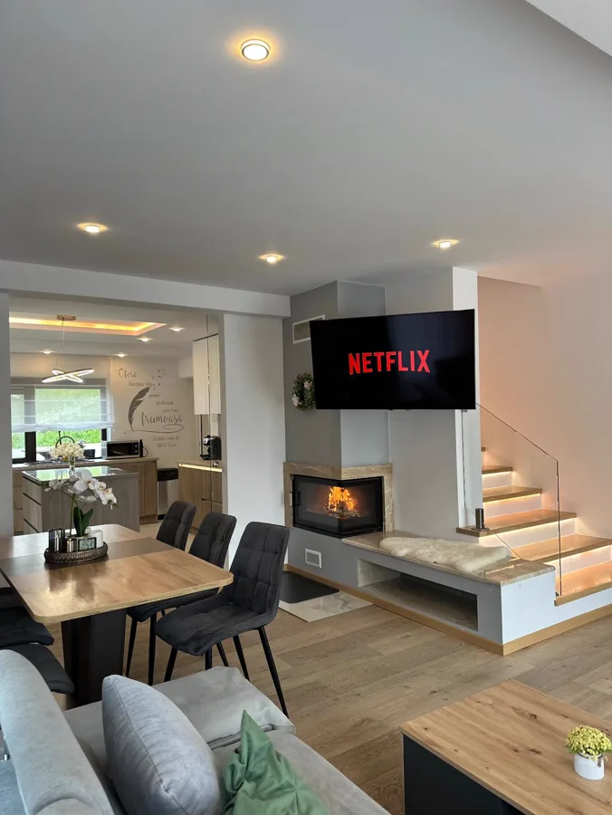 Living cu Netflix, șemineu activ și scară iluminată — seară de iarnă